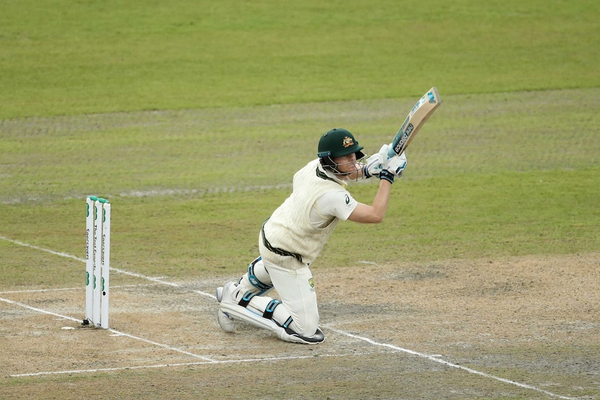 Steve Smith holds his bat up at the 45 degree angle while on his knees after playing a shot