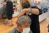 a woman cuts hair in a salon