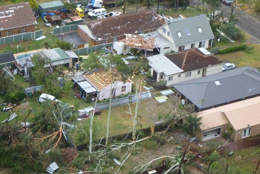 A house with it's roof ripped off among other homes with damage.
