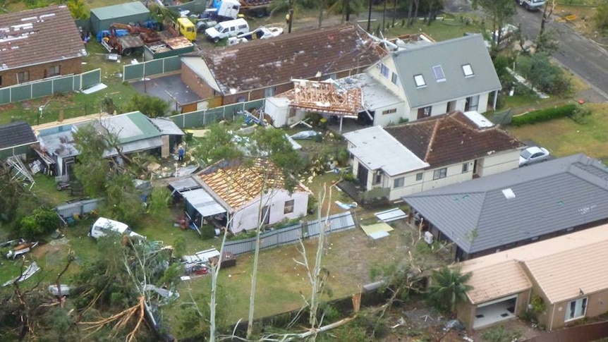 A house with it's roof ripped off among other homes with damage.