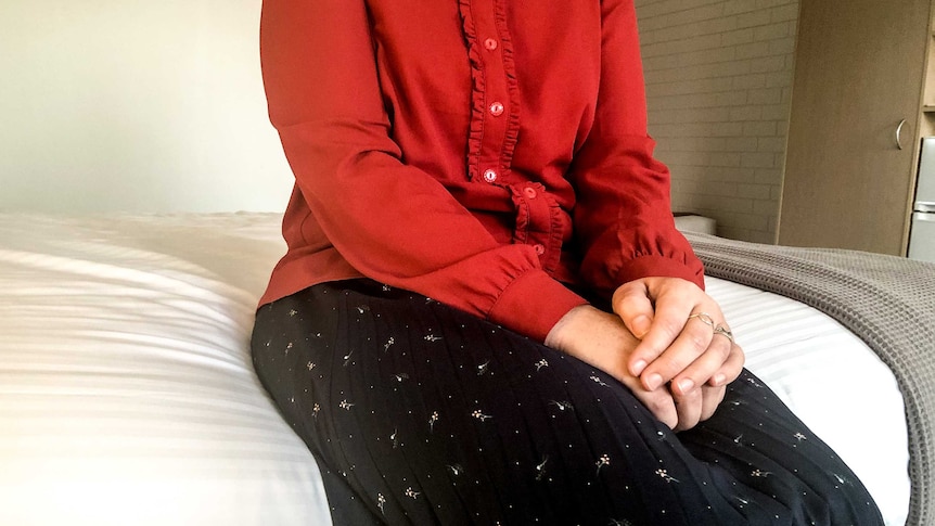 An unidentified woman sitting on a hotel bed.