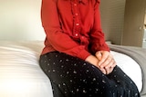 An unidentified woman sitting on a hotel bed.