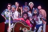 a group of aboriginal and non-indigenous artists posing with guitars and didgeridoos