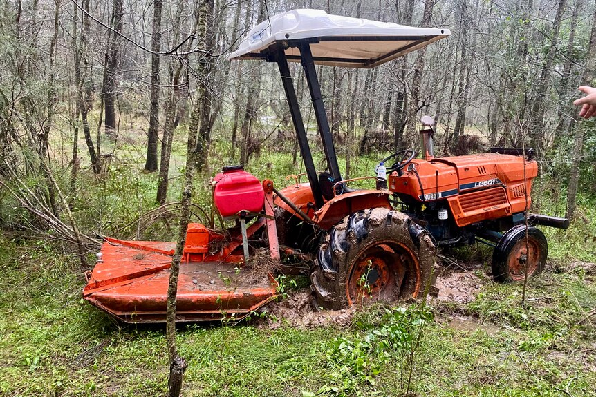 Orange tractor damaged and sunken into sodden ground