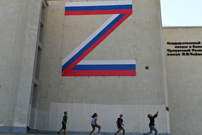 A huge letter "Z" in the colours of the Russian flag is painted on the side of a grey building.
