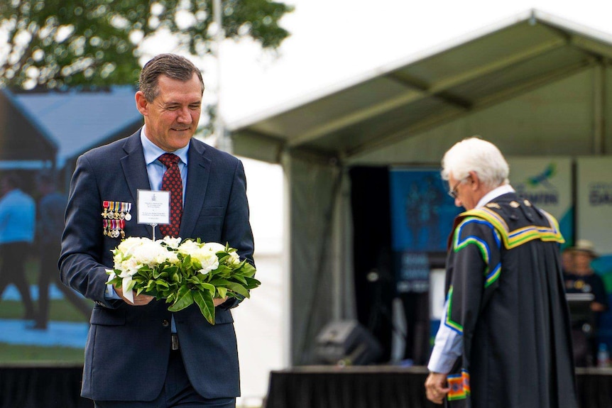 NT Chief Minister Michael Gunner, holding a wreath, stands at a Bombing of Darwin ceremony.