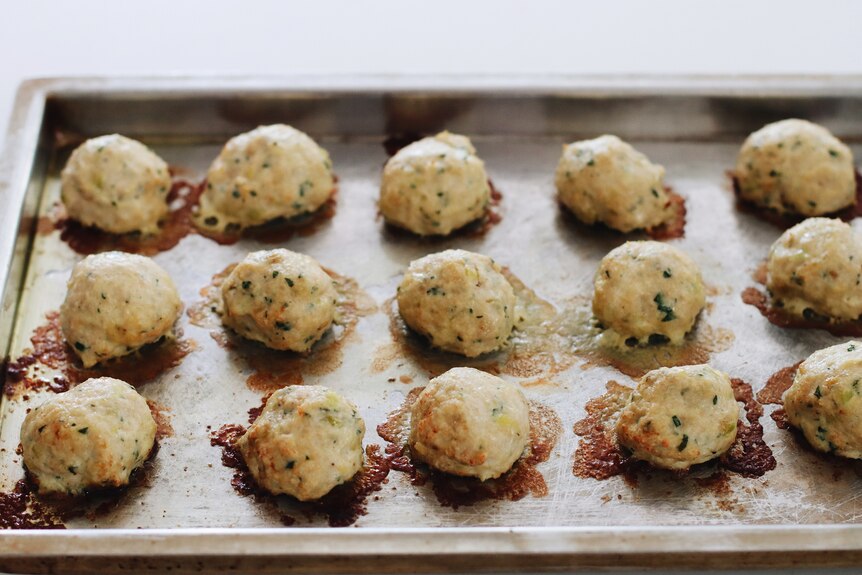 A tray of just-baked chicken, leek and parmesan meatballs, a family dinner.
