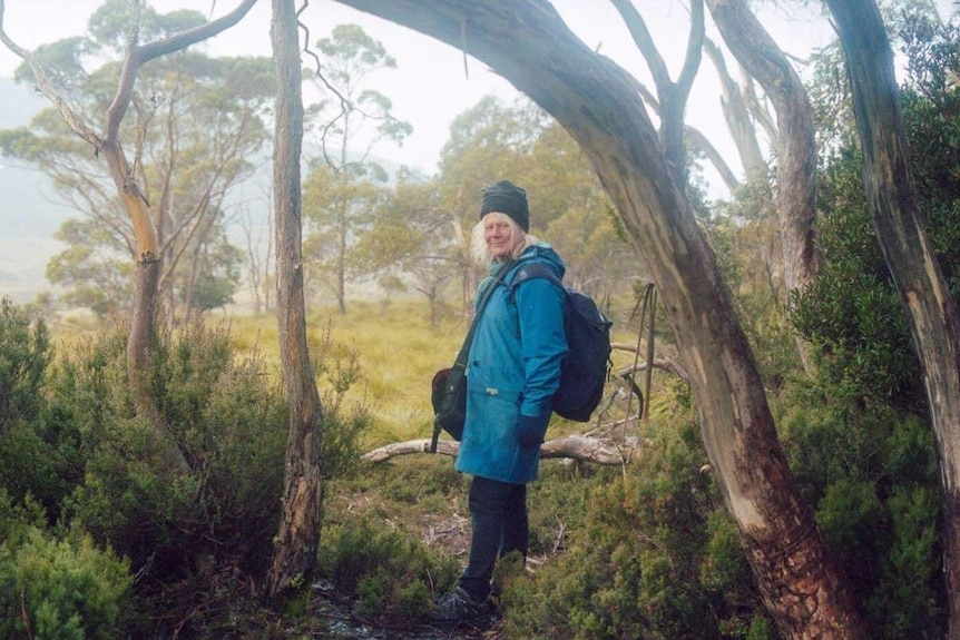 Penny Whetton stands in a bush setting under a tree, looking back at the camera.