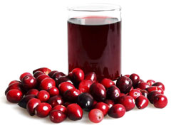 Cranberry juice in a glass with cranberries around it.