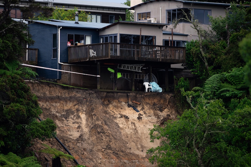 A landslide caused by flood water erodes away the earth behind a house in Auckland