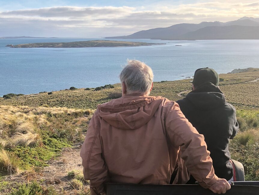 Two men perched on a four-wheeler look south across the water to Cape Barren Island.