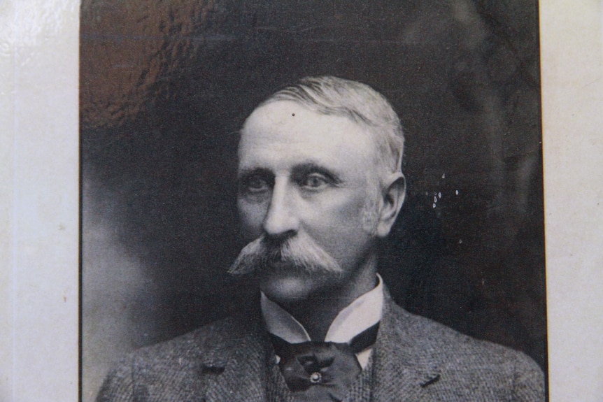 An old black and white photo of a moustached man in a suit.