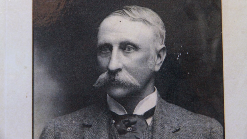 An old black and white photo of a moustached man in a suit.