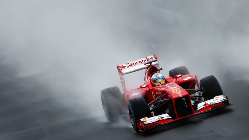 Driving rain ... Ferrari's Fernando Alonso navigates the slippery course.
