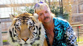 A picture of a blond man with a moustache and sparkly top with a tiger.