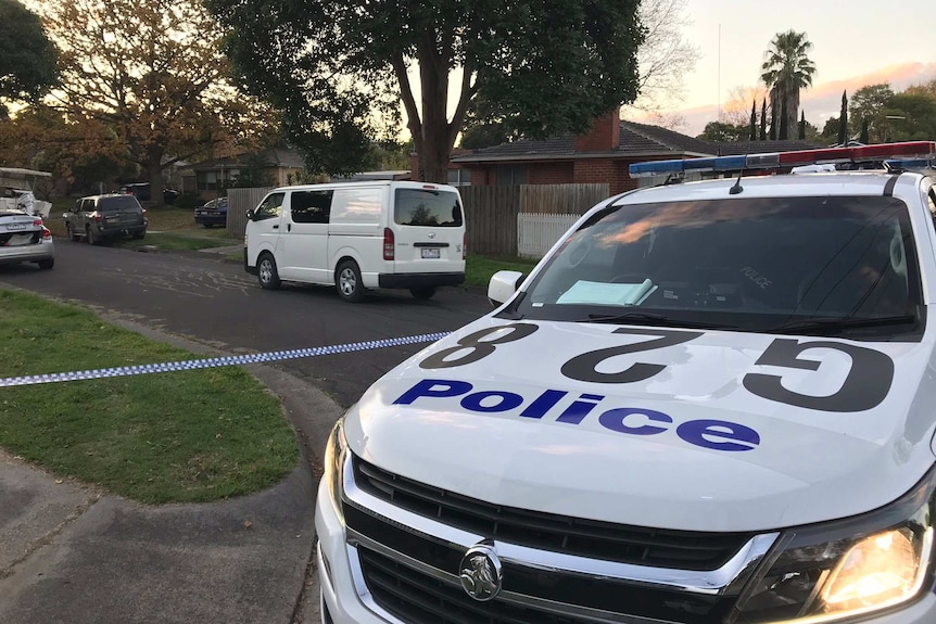 A police car and police tape in a suburban street.