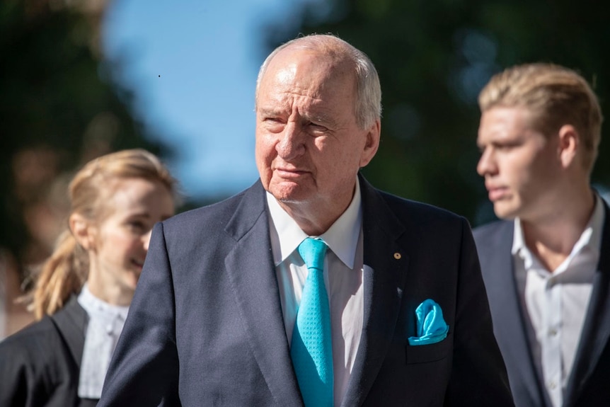 Alan Jones walks with lawyers outside the Supreme Court in Brisbane.