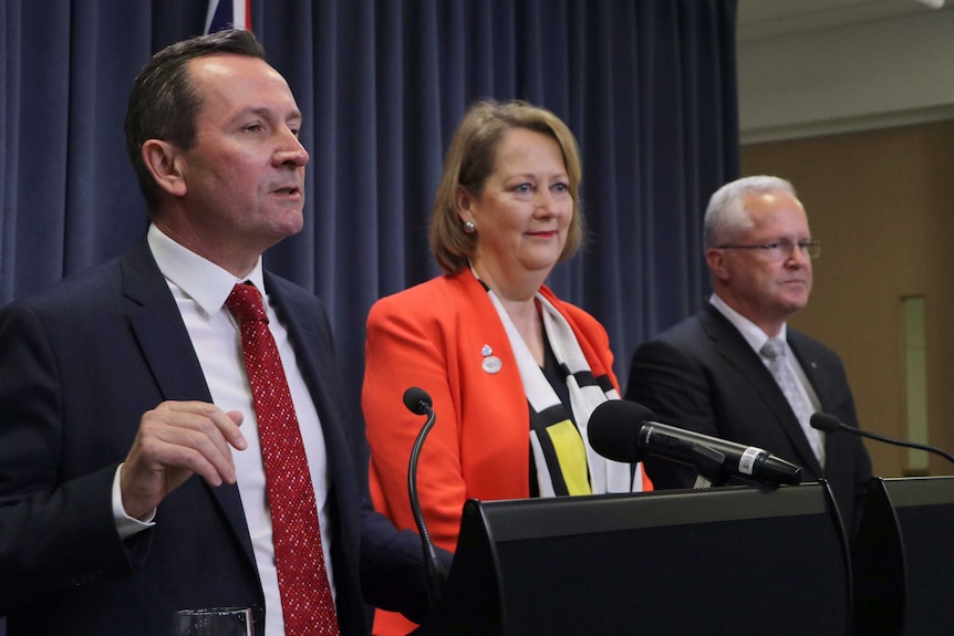 Three people standing at a lecturn.