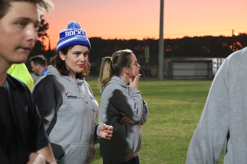 Jessica and Kellie watching the coach speak during a sunset training session.