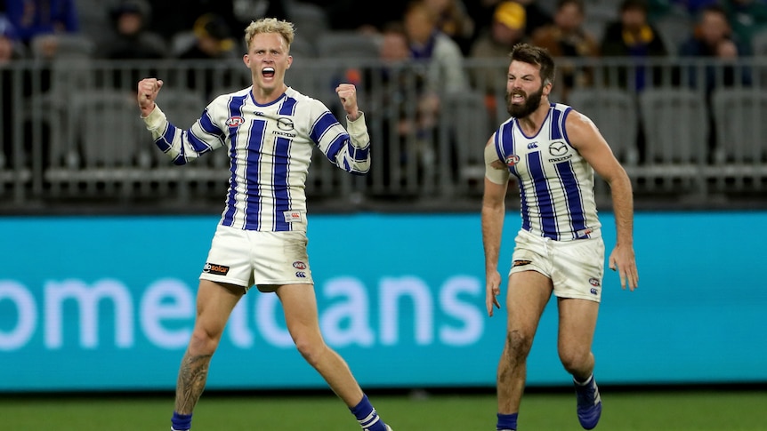 A North Melbouirne AFl player pumps his fists and roars in triumph after kicking a goal against West Coast in Perth.