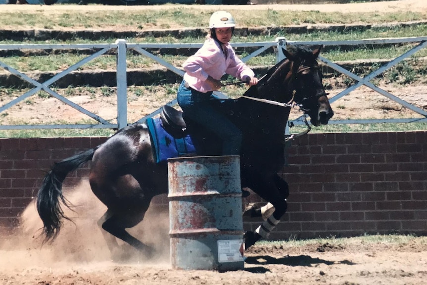 An old supplied photo of a young woman riding a horse in competition.