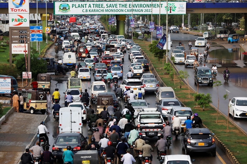 Le trafic lourd dans la ville sud-asiatique se déplace sous un pont affichant une bannière sur la plantation d'arbres