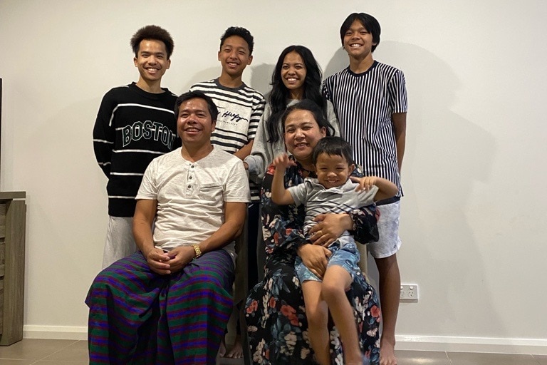 The Omtha family poses for a photo - parents with a young boy in the front and three older boys and  Ms Omtha's stand behind. 