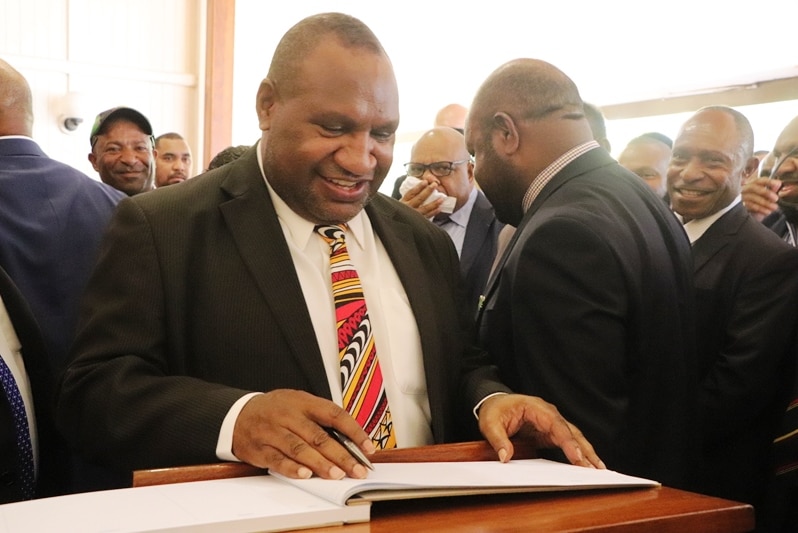 James Marape is about to write in a book.