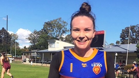 Emily Bates smiling and giving both thumbs up as she wears long sleeves and a Brisbane Lions jersey.