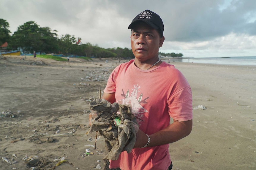 Edi Karyadi holds garbage on a Bali beach