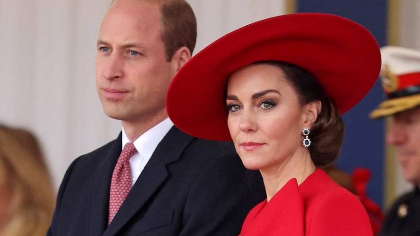 Prince William and Princess Catherine attend a ceremony. Catherine is wearing a large red hat.