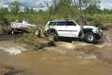 The 4wd and an attached boat are hooked on a tree in floodwaters.
