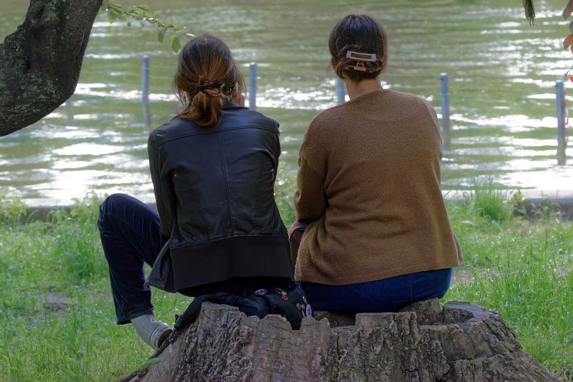 Two women sit side by side outdoors.