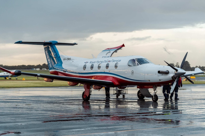 A side-on shot of a Royal Flying Doctor Service plane on the tarmac at Jandakot Airport with its door up on the far side.