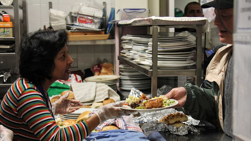 A volunteer hands over a plate of food.