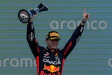 Max Verstappen on podium with trophy in hand 