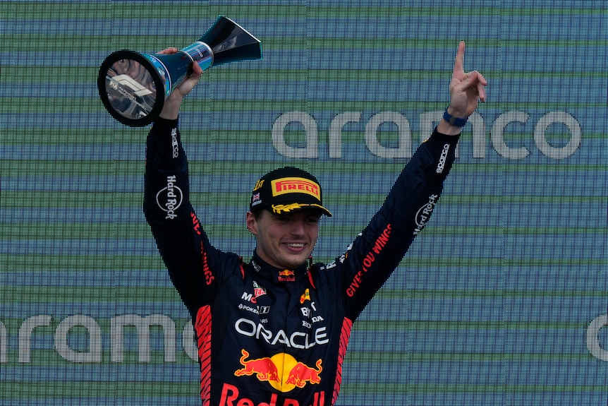 Max Verstappen on podium with trophy in hand 