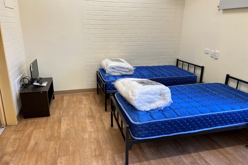 Two single beds side by side, with unmade bedding on top. A small TV in the corner of the room. Ausnew Home Care, NDIS registered provider, My Aged Care
