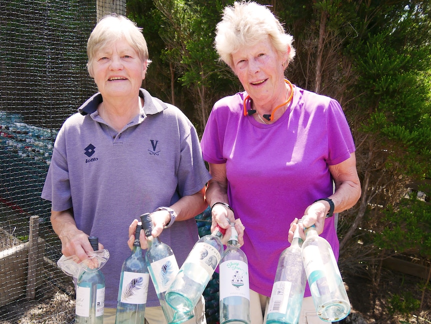 Two women holding bottles for recycling