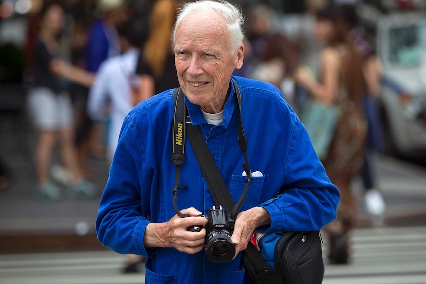 New York Times photographer Bill Cunningham crosses the street after taking photos during New York Fashion Week, 2014.