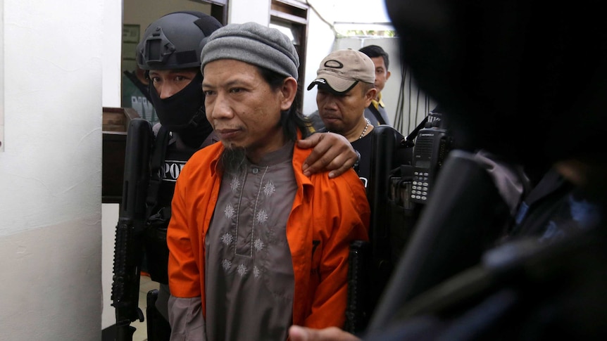 Radical Islamic cleric Aman Abdurrahman being escorted by heavily armed police in a court.