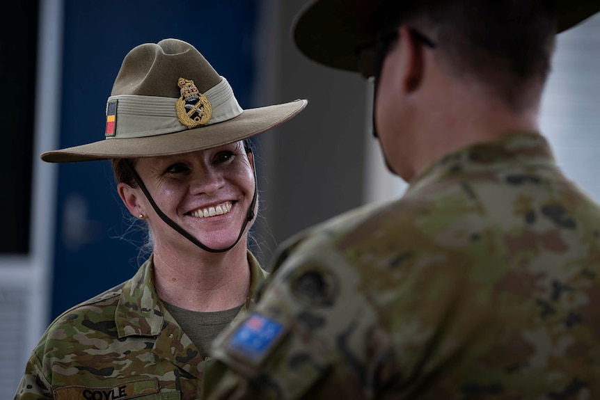 A woman in a defence uniform smiling while talking to a man in uniform.