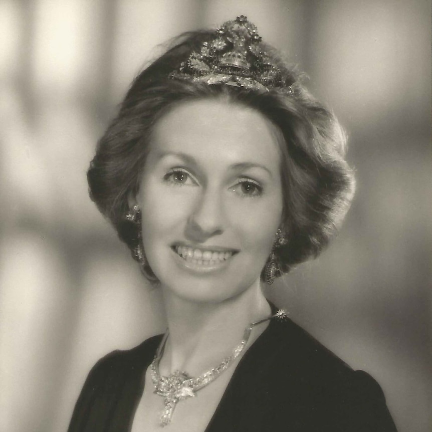 A young woman in black and white portrait wears a crown on her head and silver necklace