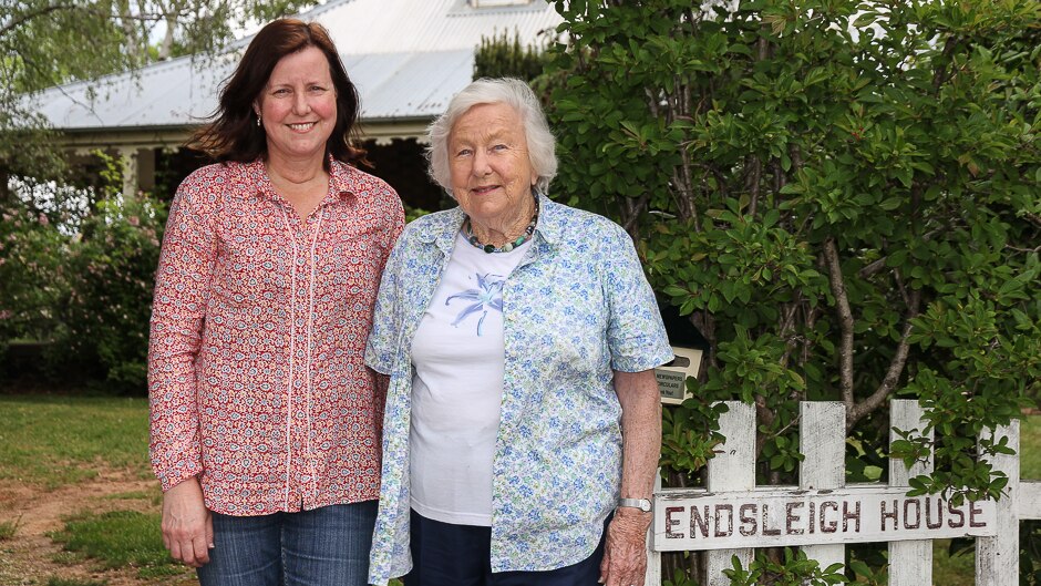 Two women standing outside a house fence with the name Endsleigh House