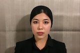A woman wearing black stares unsmiling at the camera. 
