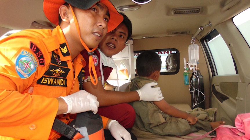 Indonesian rescue workers with survivor of ferry accident
