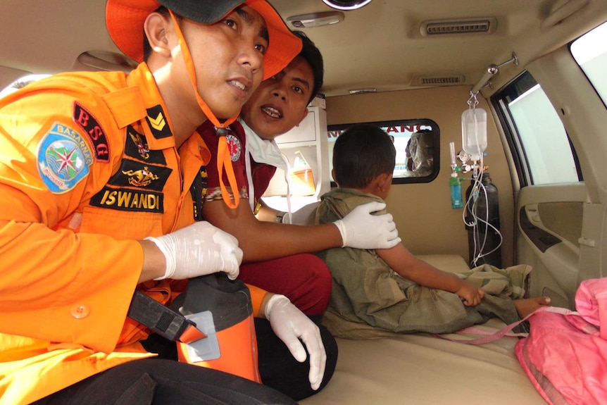 Indonesian rescue workers with survivor of ferry accident