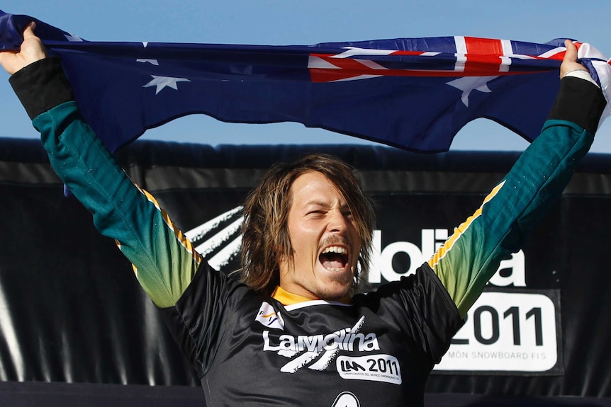 Alex Pullin screams in delight while holding an Australian flag over his head.
