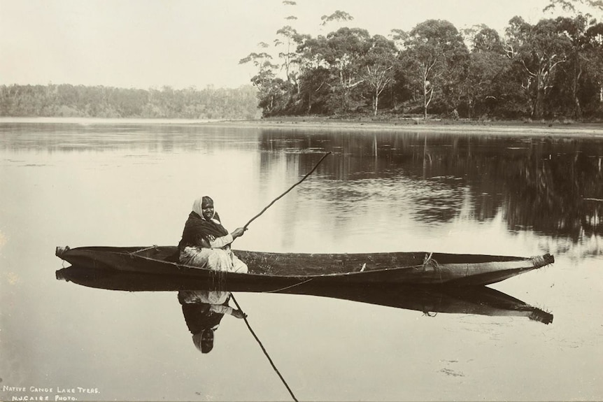 A historical photograph of an Aboriginal woman fishing in a boat 
