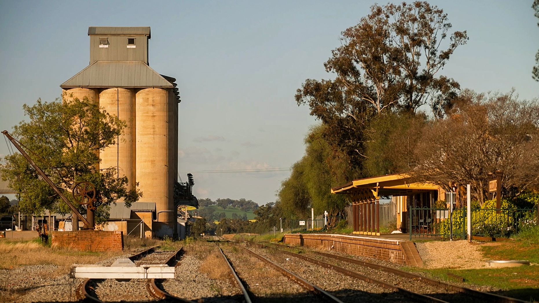 A landscape image of Coolamon train station with fields in the distance and silos across from station